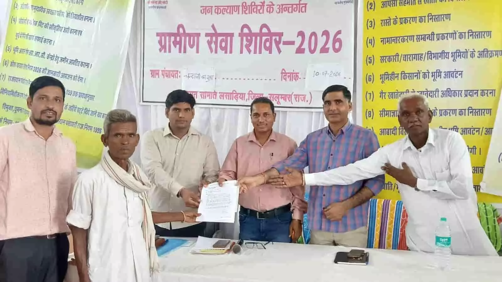 राजस्व अधिकारी ग्राम पंचायत चंदाजी का गुड़ा में किसान को दस्तावेज सौंप रहे हैं।
