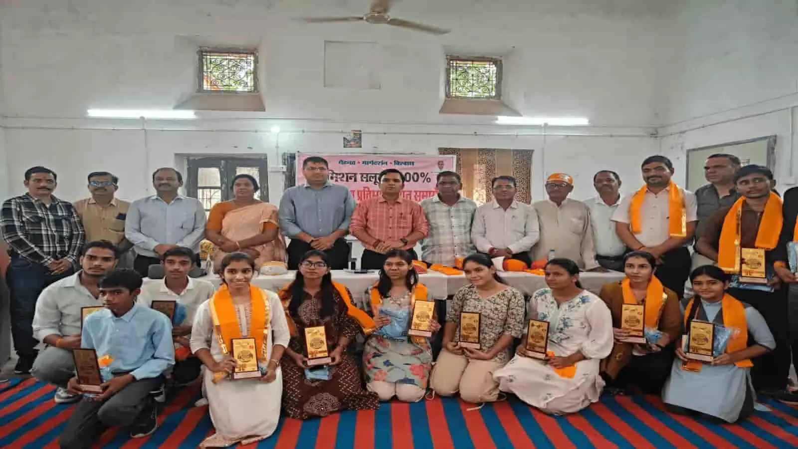 सम्मान समारोह में बोर्ड परीक्षा टॉपर्स छात्र और अधिकारी मंच पर दिख रहे हैं। सम्मान समारोह में बोर्ड परीक्षा टॉपर्स छात्र और अधिकारी मंच पर दिख रहे हैं।