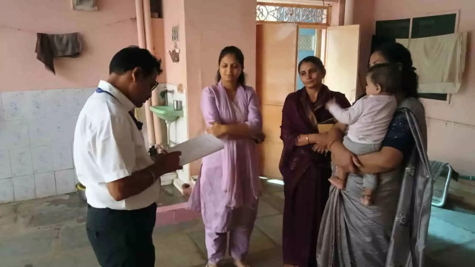 प्रतापगढ़ में बच्चों के पोषण सर्वे के दौरान अधिकारियों और महिलाओं के साथ खड़ा एक शिशु। प्रतापगढ़ में बच्चों के पोषण सर्वे के दौरान अधिकारियों और महिलाओं के साथ खड़ा एक शिशु।