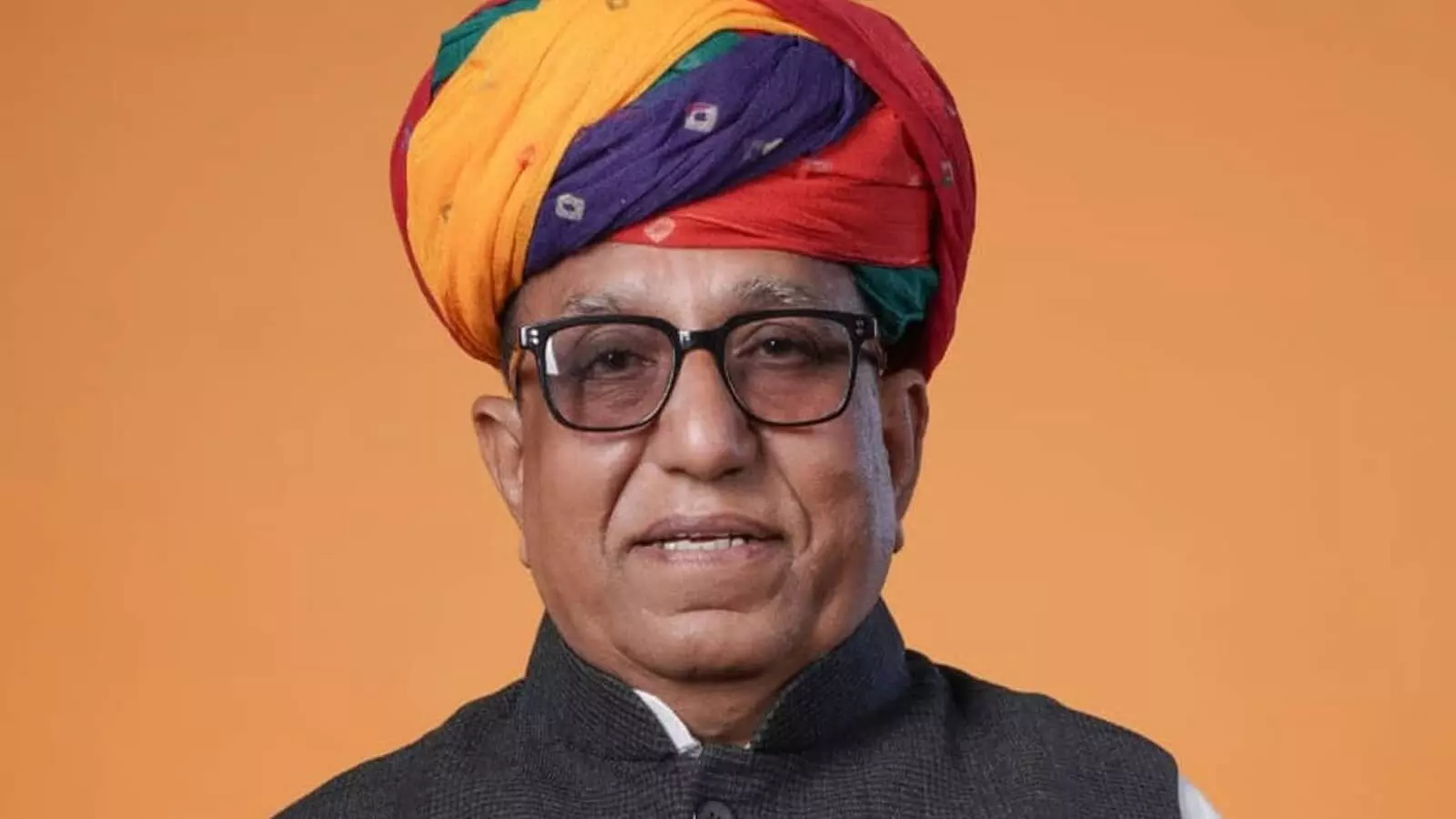 नारंगी पृष्ठभूमि के सामने बहुरंगी राजस्थानी पगड़ी और चश्मा पहने विधायक रामकेश मीणा का पोर्ट्रेट चित्र। नारंगी पृष्ठभूमि के सामने बहुरंगी राजस्थानी पगड़ी और चश्मा पहने विधायक रामकेश मीणा का पोर्ट्रेट चित्र।