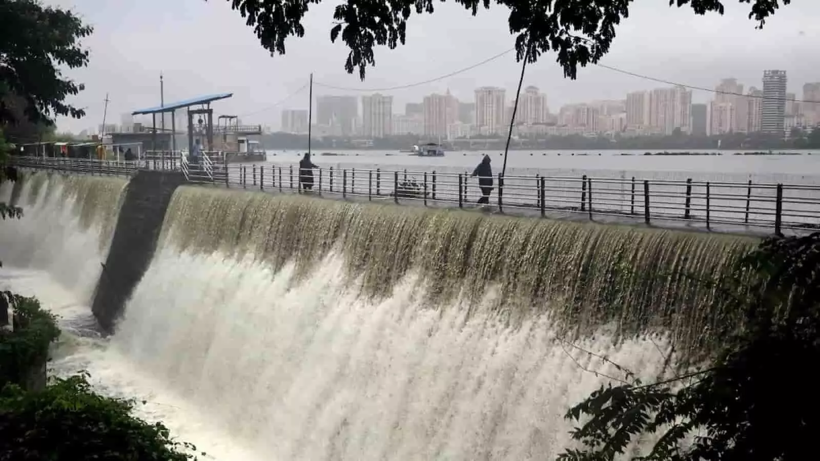 मुंबई के जलाशय से गिरता पानी और पीछे दिख रही शहर की इमारतें। मुंबई के जलाशय से गिरता पानी और पीछे दिख रही शहर की इमारतें।