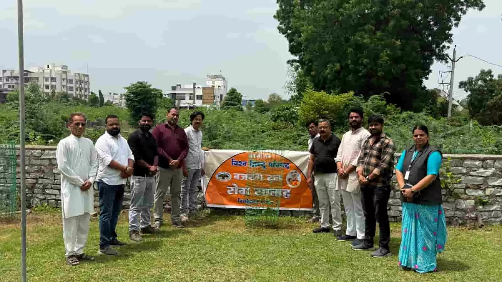 विद्यालय के मैदान में बैनर के साथ वृक्षारोपण कार्यक्रम में खड़े कार्यकर्ता। विद्यालय के मैदान में बैनर के साथ वृक्षारोपण कार्यक्रम में खड़े कार्यकर्ता।