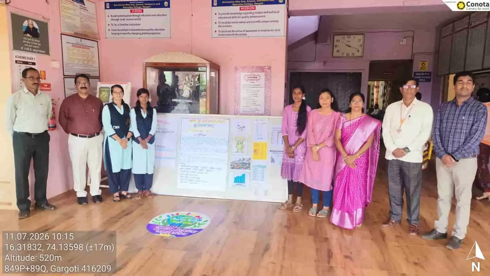 कर्मवीर हिरे महाविद्यालयातील प्राध्यापक आणि विद्यार्थी लोकसंख्या विषयावरील भित्तिपत्रकासमोर उभे आहेत.