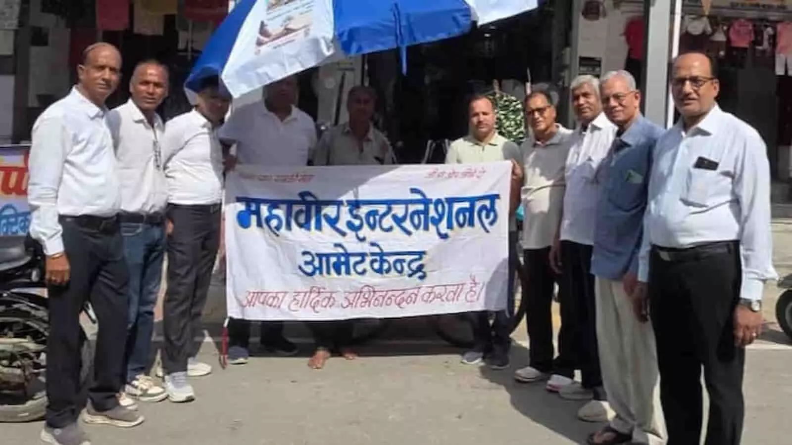 महावीर इंटरनेशनल आमेट के सदस्य सड़क पर बैनर के साथ खड़े हुए हैं। महावीर इंटरनेशनल आमेट के सदस्य सड़क पर बैनर के साथ खड़े हुए हैं।