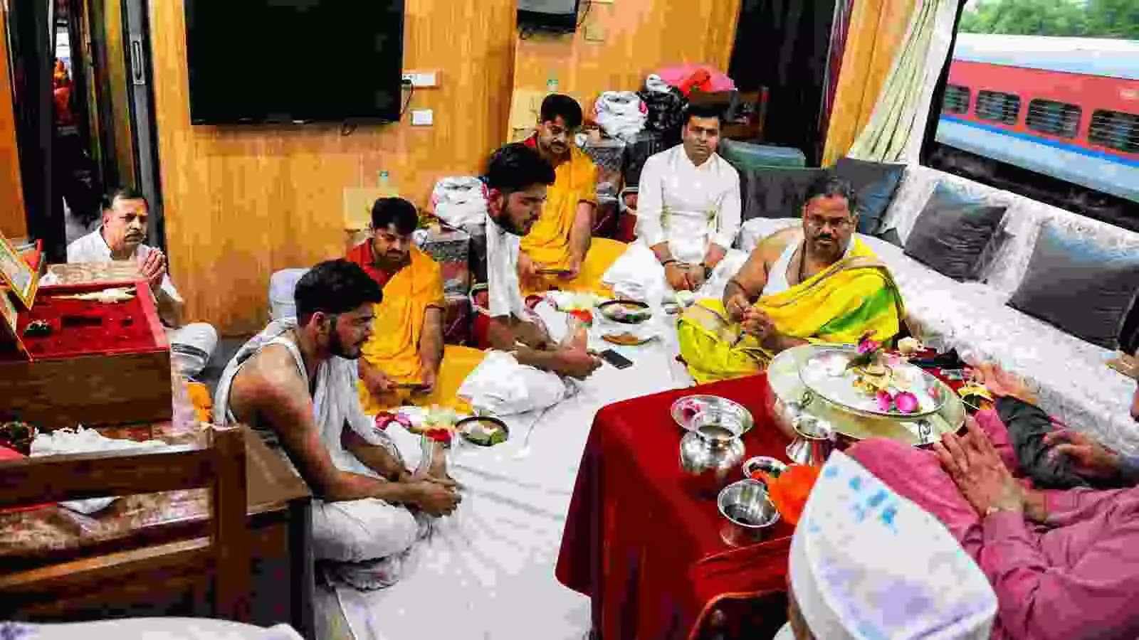सैलून कोच के अंदर पंडित द्वारा पूजा और रुद्राभिषेक किया जा रहा है।