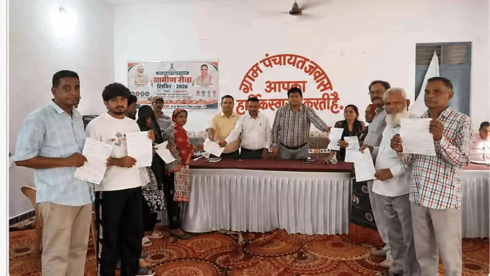 अधिकारी ग्राम पंचायत जवास में लाभार्थियों को पट्टे और पेंशन के दस्तावेज वितरित कर रहे हैं।