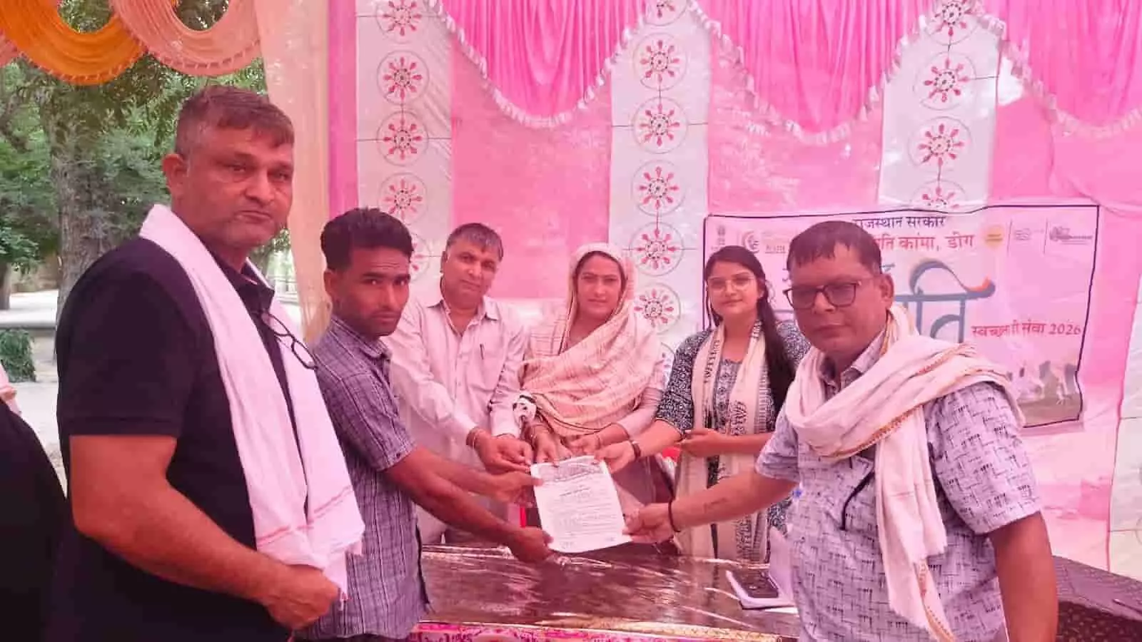 शिविर में अधिकारियों द्वारा एक ग्रामीण व्यक्ति को आवासीय भूमि का पट्टा सौंपने का दृश्य। शिविर में अधिकारियों द्वारा एक ग्रामीण व्यक्ति को आवासीय भूमि का पट्टा सौंपने का दृश्य।