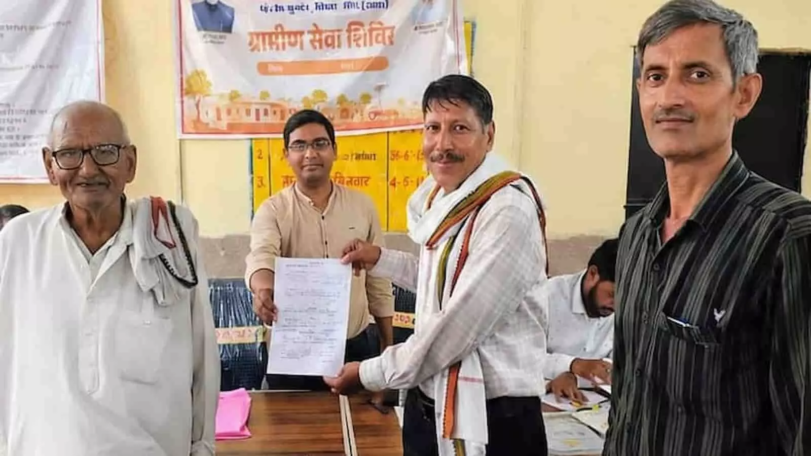 डीग में ग्रामीण सेवा शिविर के दौरान अधिकारी एक व्यक्ति को दस्तावेज प्रदान कर रहे हैं। डीग में ग्रामीण सेवा शिविर के दौरान अधिकारी एक व्यक्ति को दस्तावेज प्रदान कर रहे हैं।