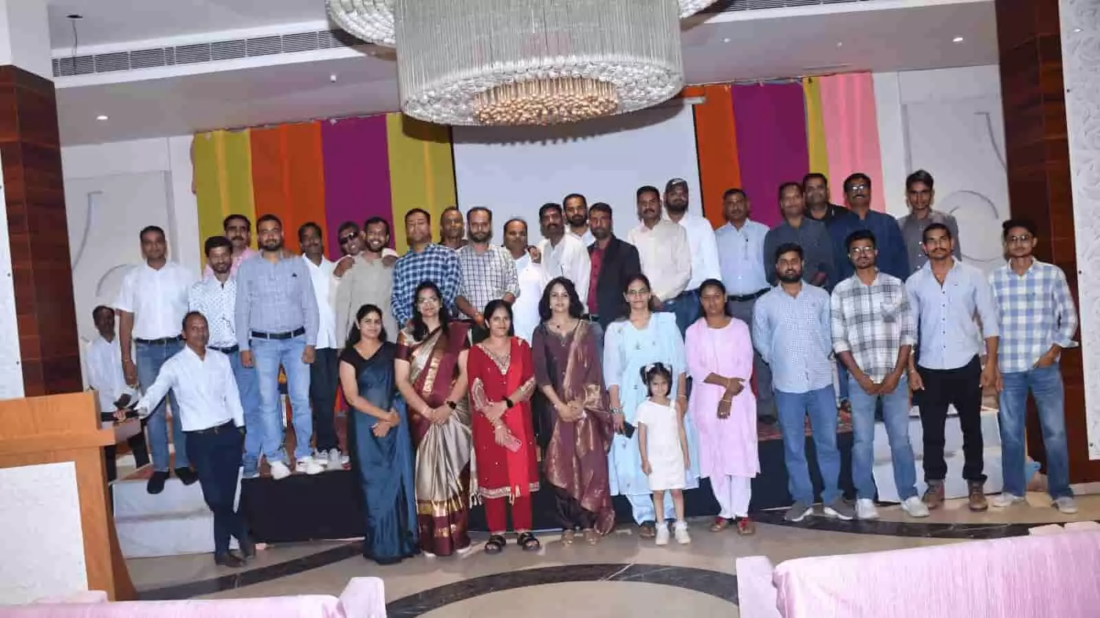 तस्वीर में मंच पर अधिकारी, फार्मासिस्ट और सहभागी सामूहिक फोटो के दौरान समारोह स्थल पर खड़े हैं।
