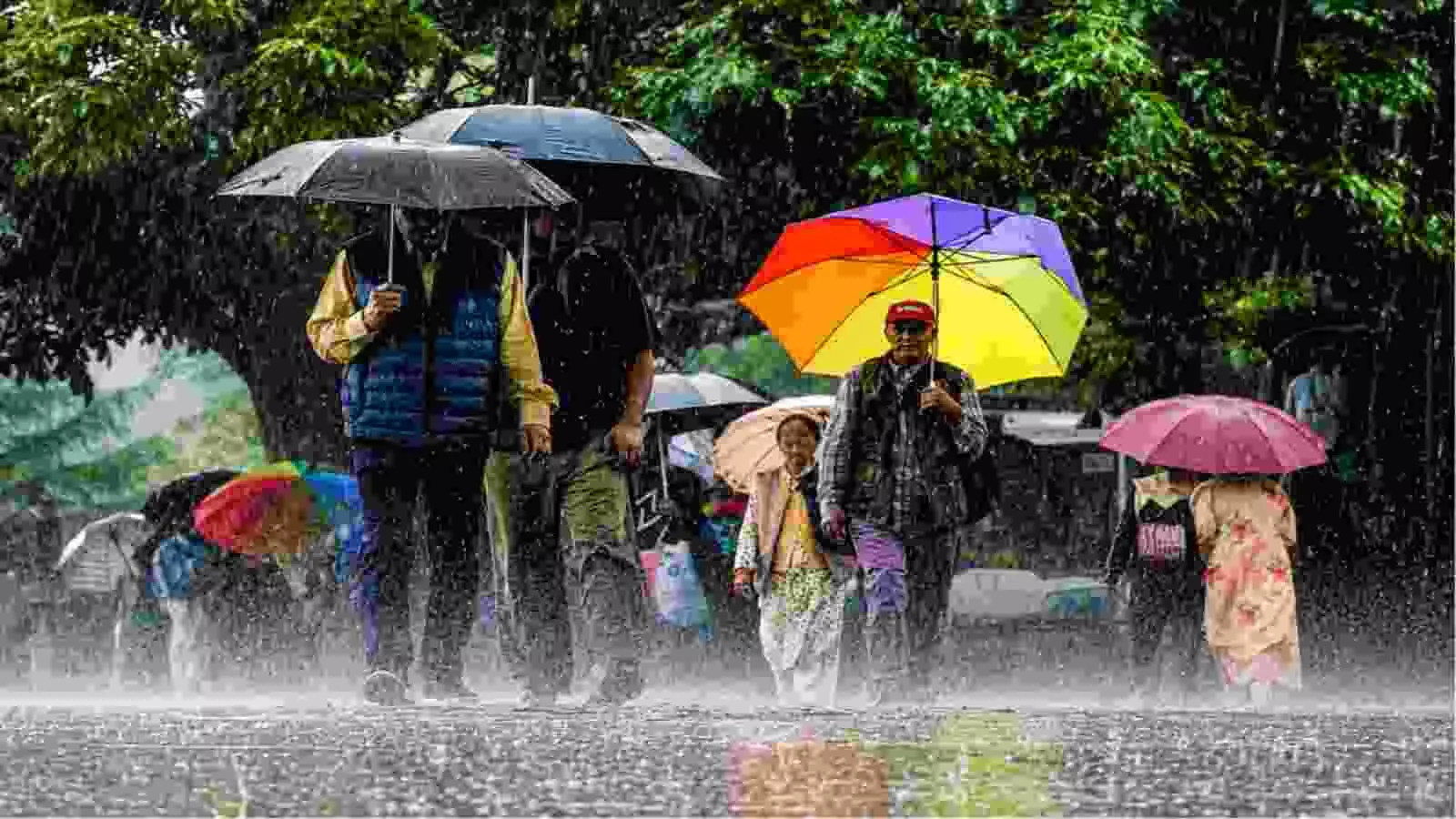 भारी बारिश के दौरान छाता लेकर चलते लोग|