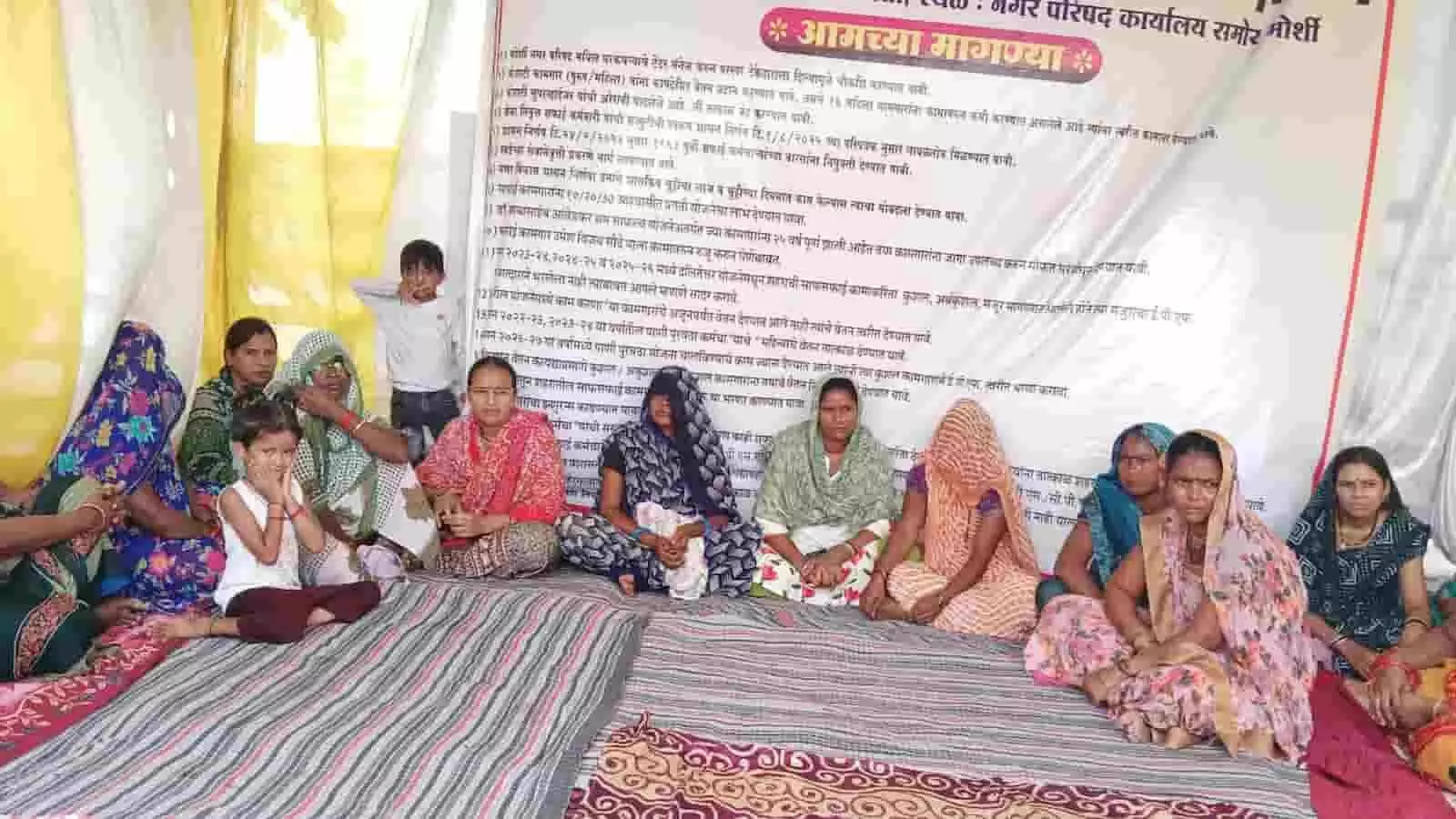 मोर्शी नगरपरिषद कार्यालय के बाहर बैनर के सामने बैठी महिला सफाई कर्मचारी। मोर्शी नगरपरिषद कार्यालय के बाहर बैनर के सामने बैठी महिला सफाई कर्मचारी।