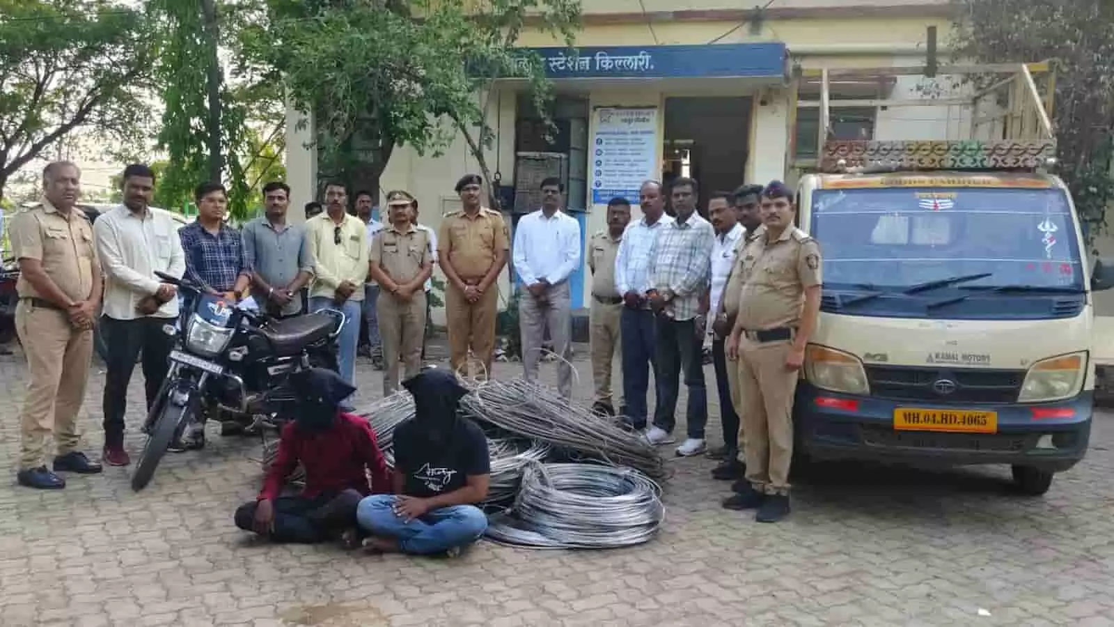 किल्लारी पुलिस स्टेशन के बाहर पुलिस अधिकारियों के साथ खड़े लोग और जमीन पर बैठे दो आरोपी।