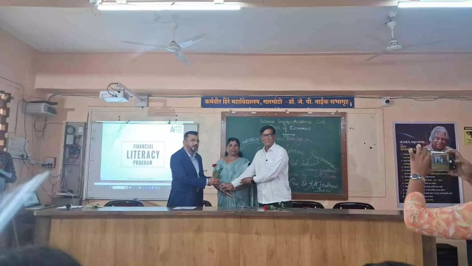 तस्वीर में गारगोटी कॉलेज के सभागार में मंच पर आर्थिक साक्षरता कार्यशाला का आयोजन दिख रहा है।