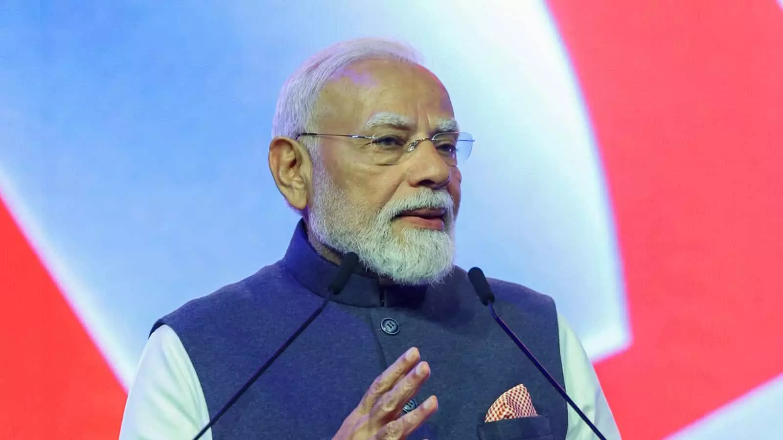मंच पर पोडियम के सामने माइक्रोफोन पर बोलते हुए प्रधानमंत्री नरेंद्र मोदी। मंच पर पोडियम के सामने माइक्रोफोन पर बोलते हुए प्रधानमंत्री नरेंद्र मोदी।