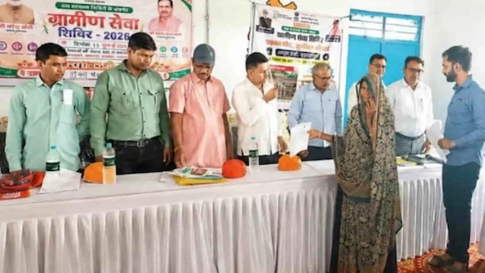 तस्वीर में ग्रामीण सेवा शिविर के दौरान अधिकारी एक महिला को पेंशन के दस्तावेज सौंपते हुए दिख रहे हैं। तस्वीर में ग्रामीण सेवा शिविर के दौरान अधिकारी एक महिला को पेंशन के दस्तावेज सौंपते हुए दिख रहे हैं।