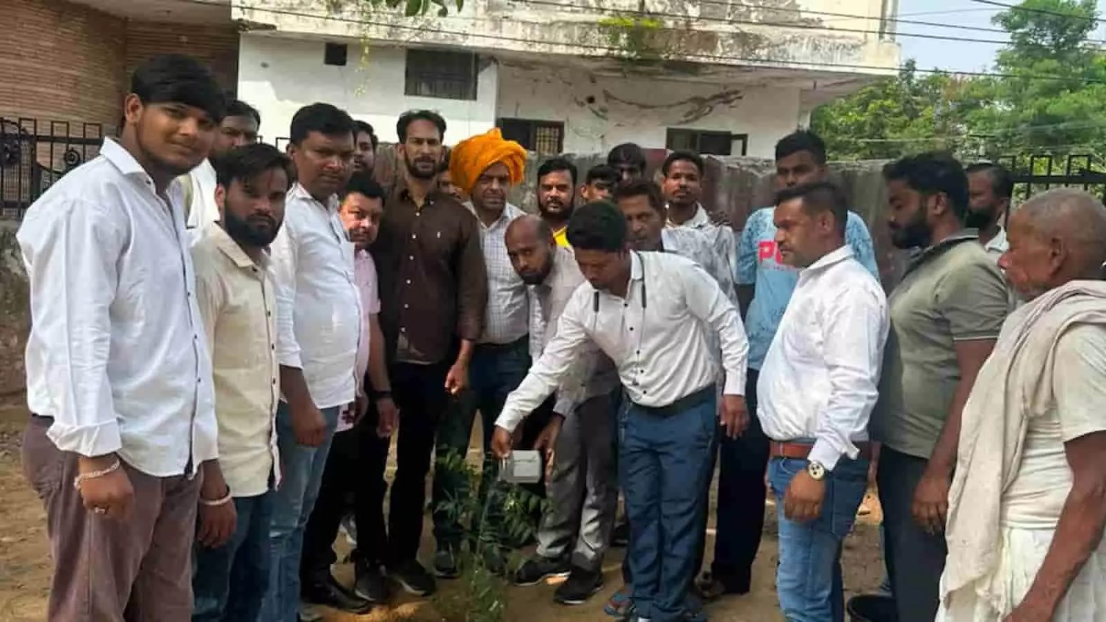 तस्वीर में पार्क के भीतर जमीन पर एक नया पौधा लगाते हुए पुरुषों का समूह दिख रहा है। तस्वीर में पार्क के भीतर जमीन पर एक नया पौधा लगाते हुए पुरुषों का समूह दिख रहा है।