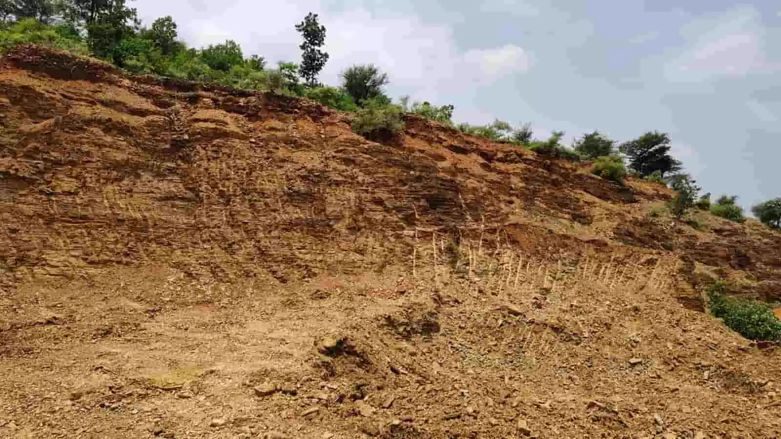 घोसुंडी में मिट्टी के खनन से बनी गहरे गड्ढों वाली एक ढलान दिखाई दे रही है। घोसुंडी में मिट्टी के खनन से बनी गहरे गड्ढों वाली एक ढलान दिखाई दे रही है।