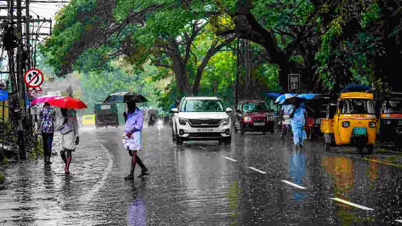 केरल में हल्की बारिश के बीच सड़क पर चलते लोग और यातायात का दृश्य। केरल में हल्की बारिश के बीच सड़क पर चलते लोग और यातायात का दृश्य।
