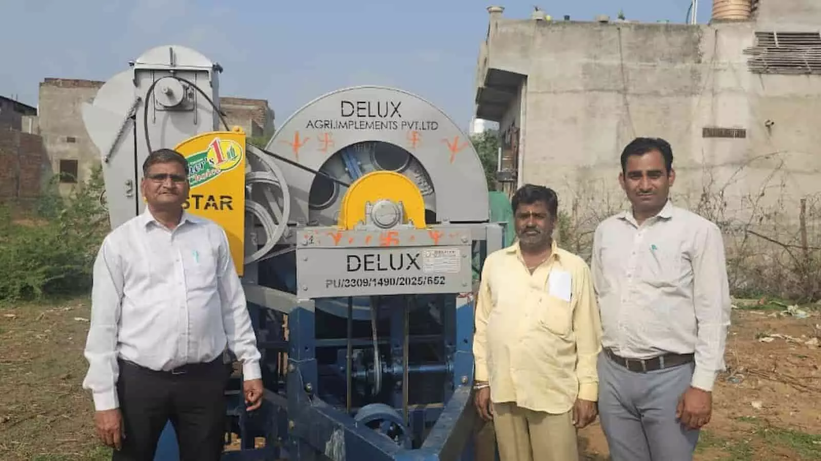 ग्रामीण सेवा शिविर में आधुनिक मल्टीक्रॉप थ्रेसर मशीन के सामने खड़े तीन ग्रामीण पुरुष। ग्रामीण सेवा शिविर में आधुनिक मल्टीक्रॉप थ्रेसर मशीन के सामने खड़े तीन ग्रामीण पुरुष।