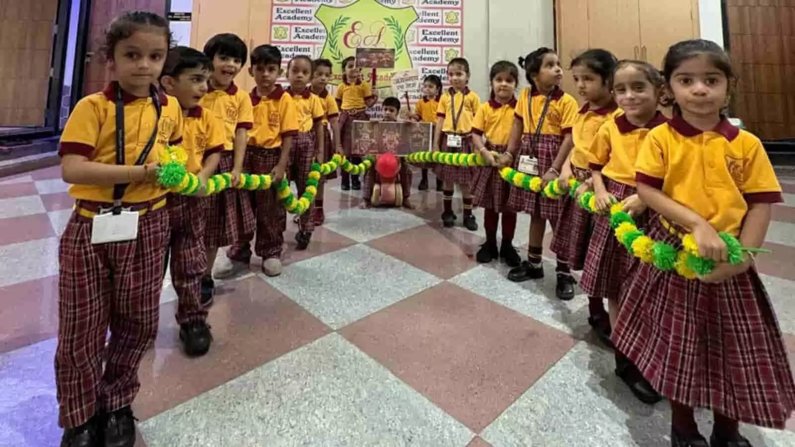 स्कूल के हॉल में कतारबद्ध खड़े होकर हाथ में फूलों की माला थामे छोटे बच्चे। स्कूल के हॉल में कतारबद्ध खड़े होकर हाथ में फूलों की माला थामे छोटे बच्चे।