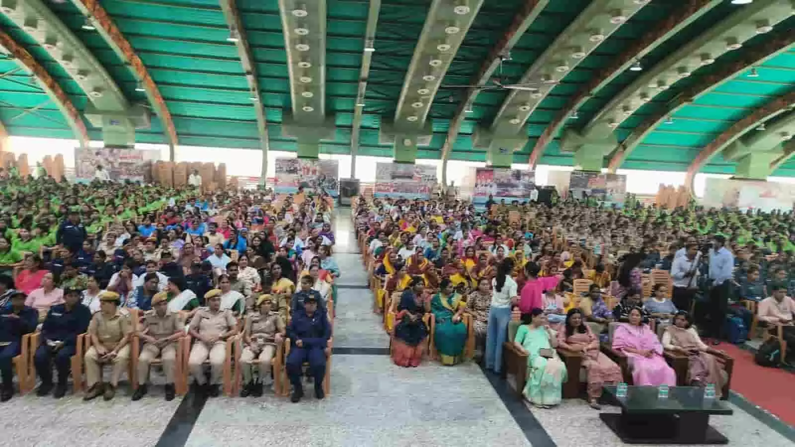 बड़े हॉल में आयोजित कार्यक्रम के दौरान कुर्सियों पर बैठी महिला पुलिसकर्मी और अन्य महिलाएं। बड़े हॉल में आयोजित कार्यक्रम के दौरान कुर्सियों पर बैठी महिला पुलिसकर्मी और अन्य महिलाएं।
