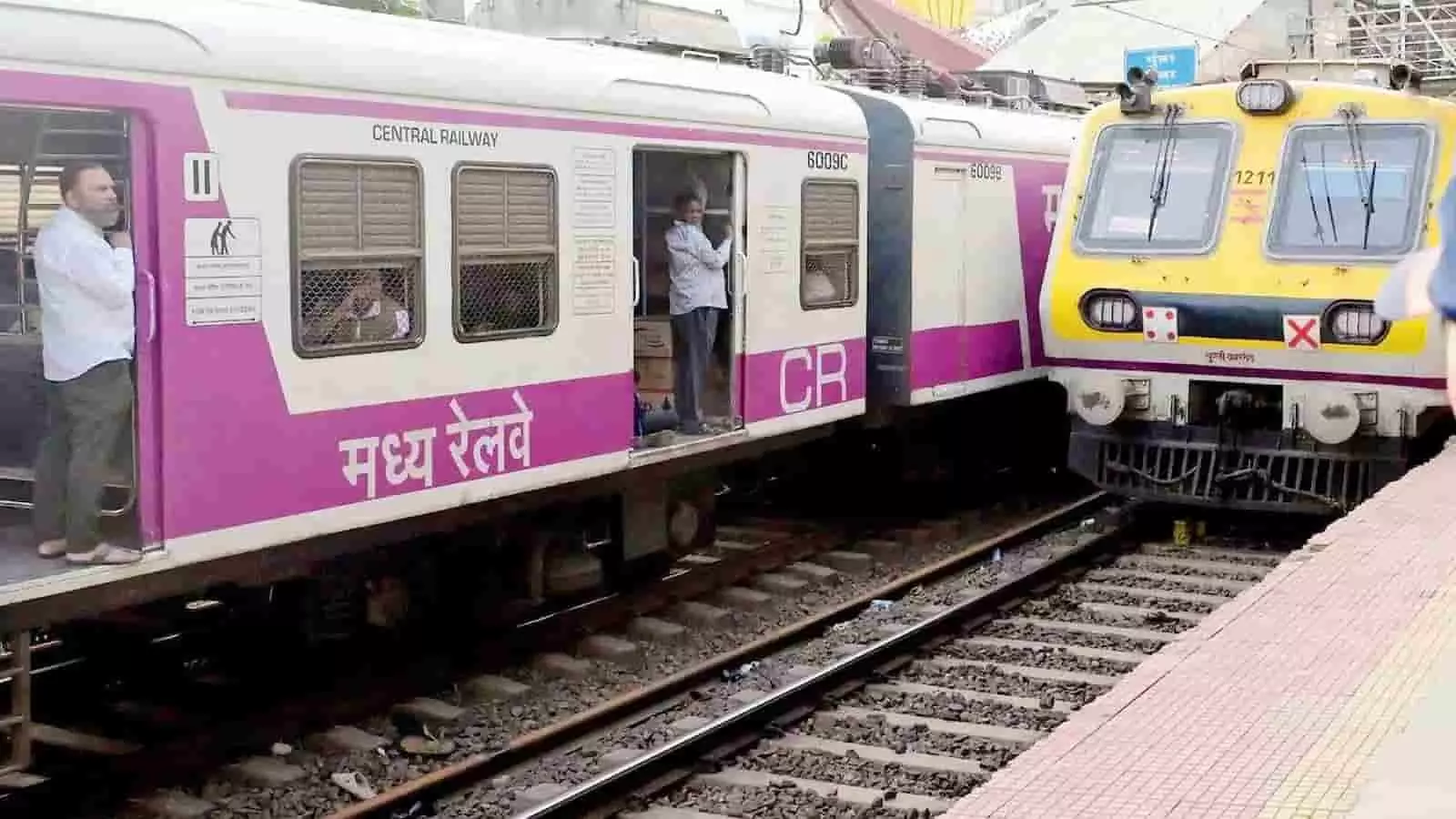 सेंट्रल रेलवे की लोकल ट्रेन के दरवाजे पर खड़ा एक यात्री और बगल में दूसरी ट्रेन। सेंट्रल रेलवे की लोकल ट्रेन के दरवाजे पर खड़ा एक यात्री और बगल में दूसरी ट्रेन।