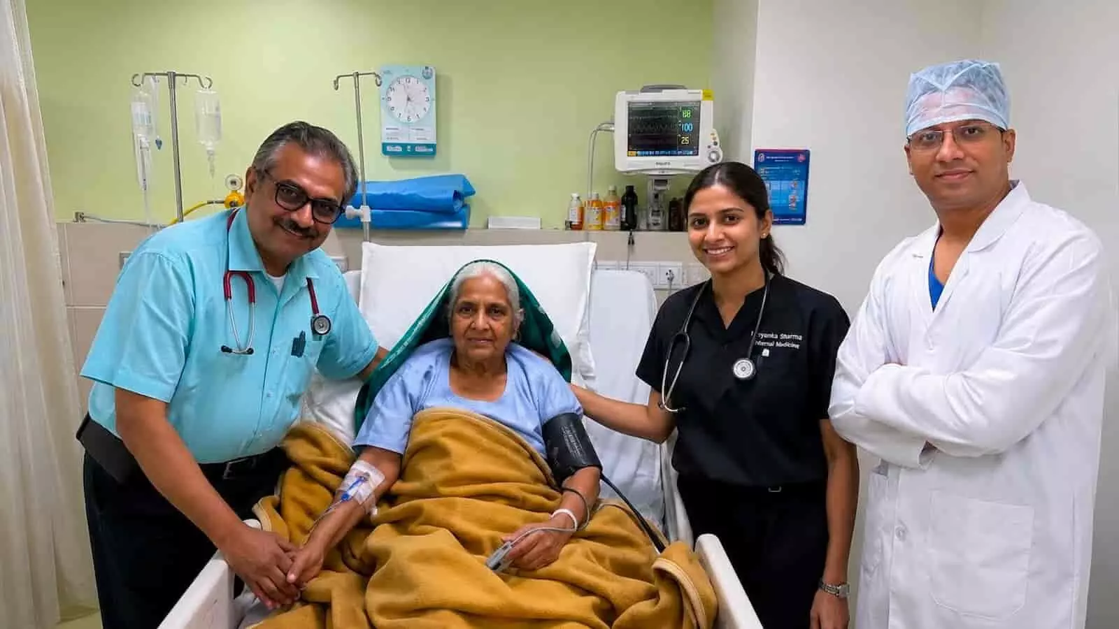 अस्पताल के बिस्तर पर लेटी महिला मरीज के साथ खड़े तीन डॉक्टर। अस्पताल के बिस्तर पर लेटी महिला मरीज के साथ खड़े तीन डॉक्टर।