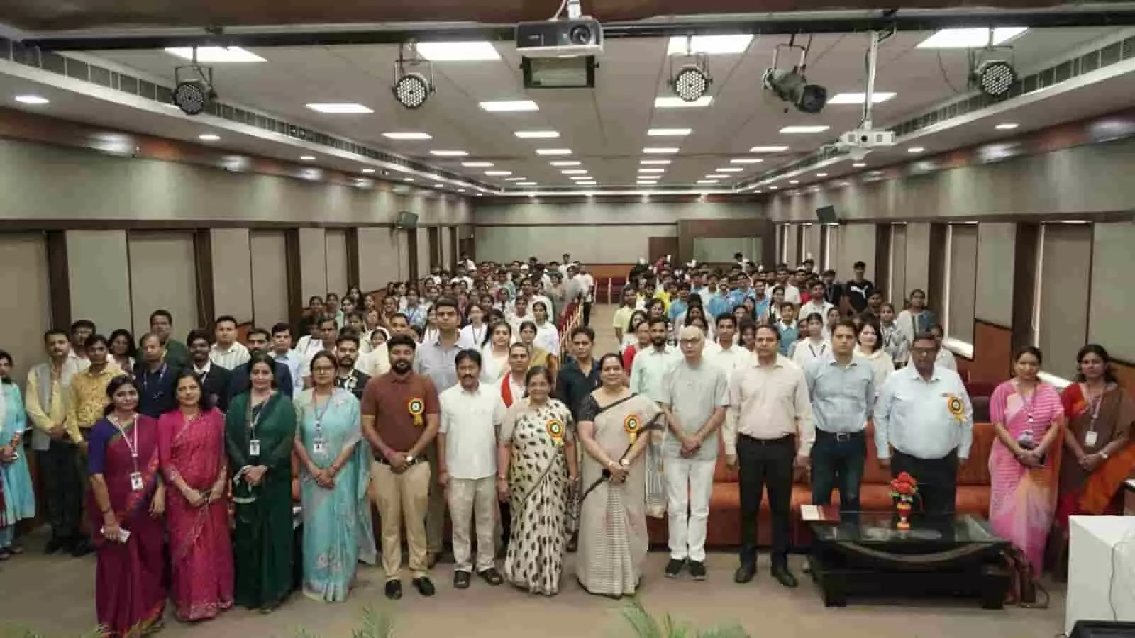 तस्वीर में एक बड़े सभागार के मंच पर गणमान्य लोग और छात्र समूह फोटो के लिए खड़े हैं। तस्वीर में एक बड़े सभागार के मंच पर गणमान्य लोग और छात्र समूह फोटो के लिए खड़े हैं।