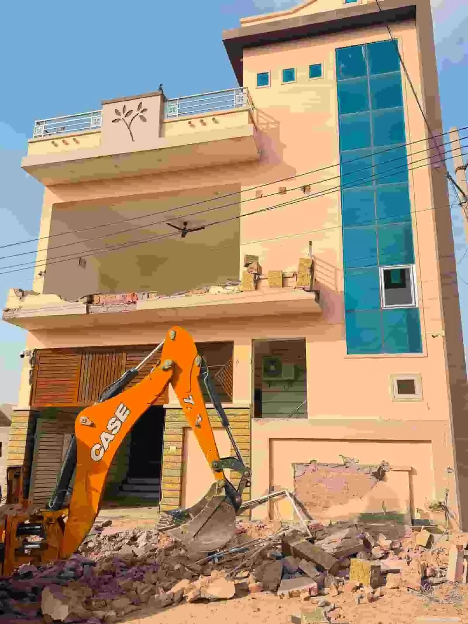 तस्वीर में बीकानेर के गंगाशहर में एक तीन मंजिला मकान के अवैध निर्माण को जेसीबी मशीन से ध्वस्त करते हुए दिखाया गया है। तस्वीर में बीकानेर के गंगाशहर में एक तीन मंजिला मकान के अवैध निर्माण को जेसीबी मशीन से ध्वस्त करते हुए दिखाया गया है।