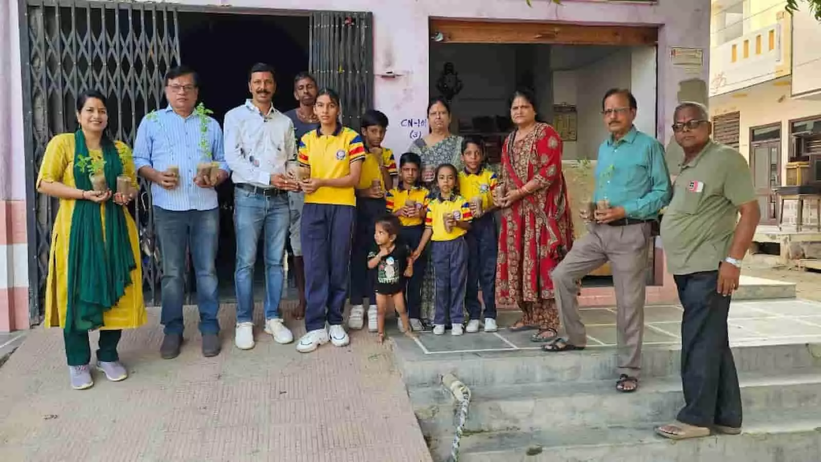 वनवासी कल्याण परिषद के सदस्य और बच्चे तेलीखेड़ा में तुलसी के पौधे पकड़े हुए हैं।