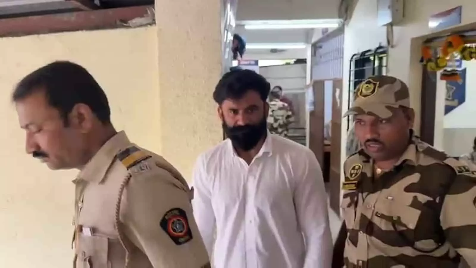 पुलिस स्टेशन परिसर में पुलिस कर्मियों की हिरासत में जाता हुआ दाढ़ी वाला आरोपी पुरुष। पुलिस स्टेशन परिसर में पुलिस कर्मियों की हिरासत में जाता हुआ दाढ़ी वाला आरोपी पुरुष।