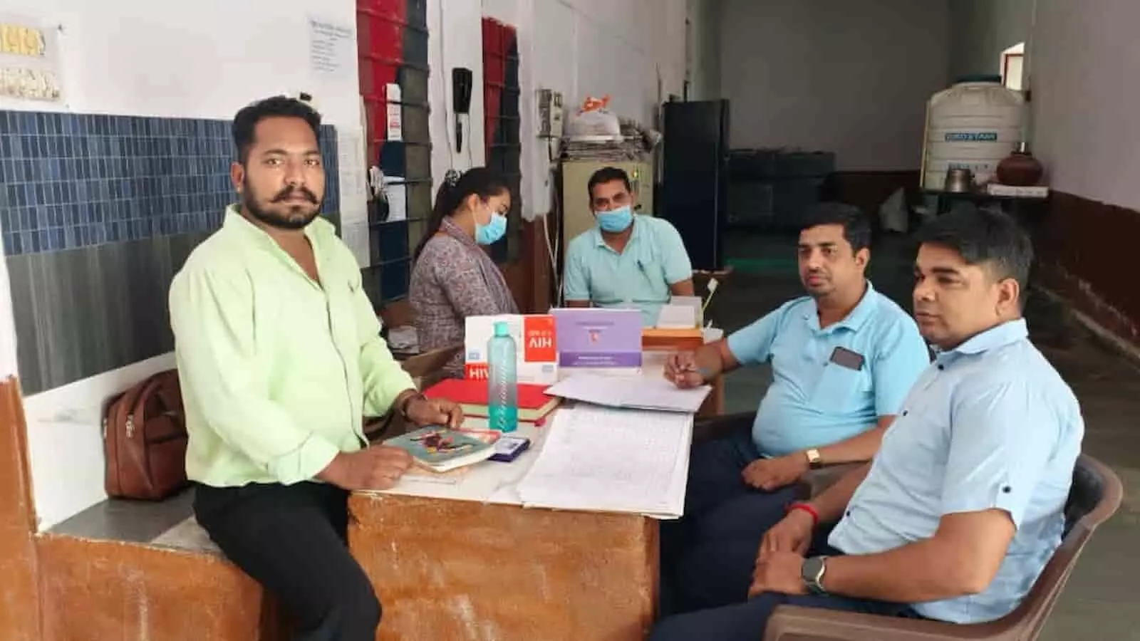 गंगापुर उपकारागृह में स्वास्थ्य शिविर के दौरान मेज पर चिकित्सकीय दस्तावेजों के साथ बैठे स्वास्थ्यकर्मी।