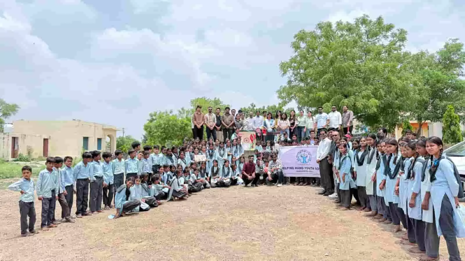 निम्बाहेड़ा विद्यालय में हेल्पिंग हैंड यूथ सोसायटी के सदस्य और विद्यार्थी साथ खड़े हैं।