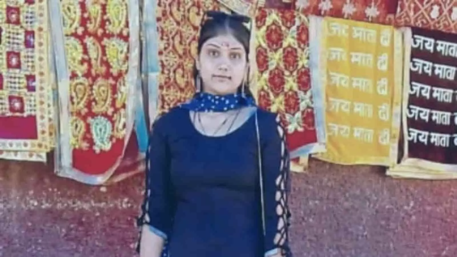 तस्वीर में नीले रंग के सूट में खड़ी युवती तप्ती, पृष्ठभूमि में धार्मिक वस्त्र दिखाई दे रहे हैं। तस्वीर में नीले रंग के सूट में खड़ी युवती तप्ती, पृष्ठभूमि में धार्मिक वस्त्र दिखाई दे रहे हैं।