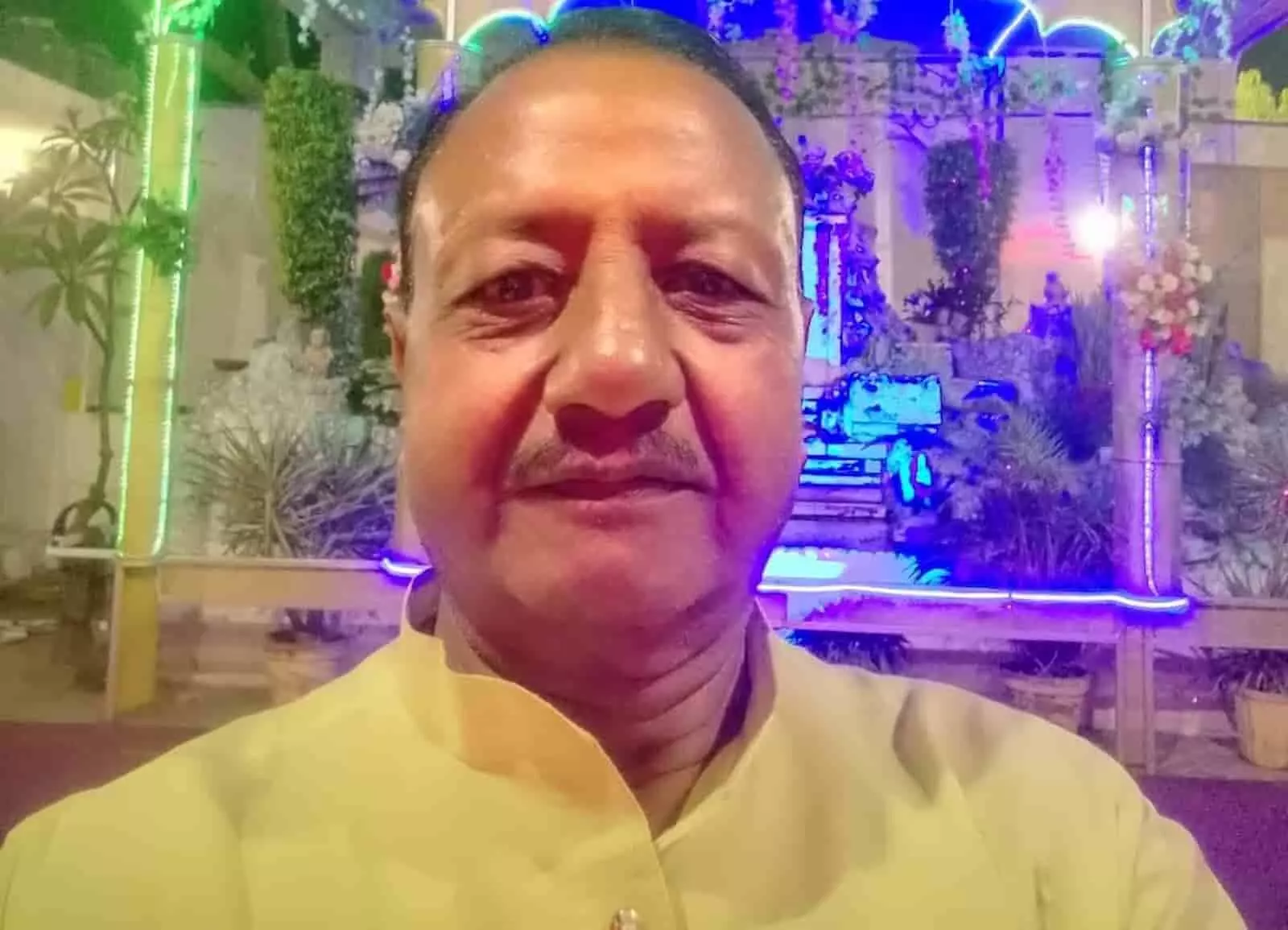 तस्वीर में व्यवसायी वेद प्रकाश मंगल एक सजावटी मंच के सामने खड़े हैं। तस्वीर में व्यवसायी वेद प्रकाश मंगल एक सजावटी मंच के सामने खड़े हैं।