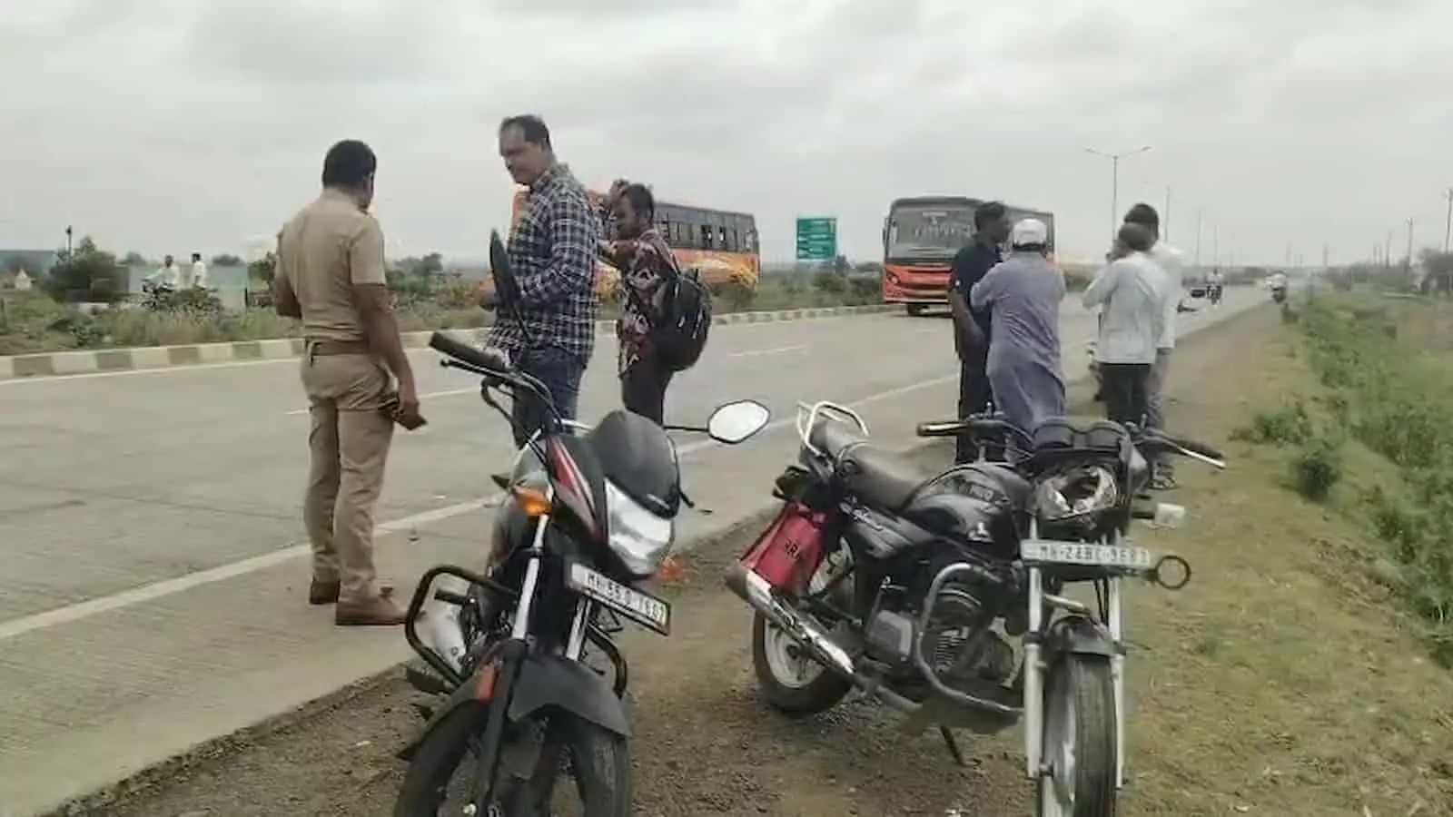 तस्वीर में हाईवे के किनारे खड़ी दो दुर्घटनाग्रस्त मोटरसाइकिलें और जांच करते पुलिसकर्मी दिख रहे हैं।