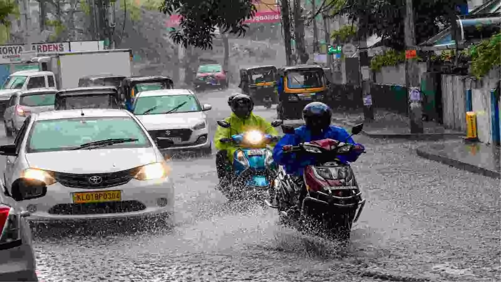 बारिश के दौरान केरल की सड़क पर चलते वाहन और दोपहिया चालक।