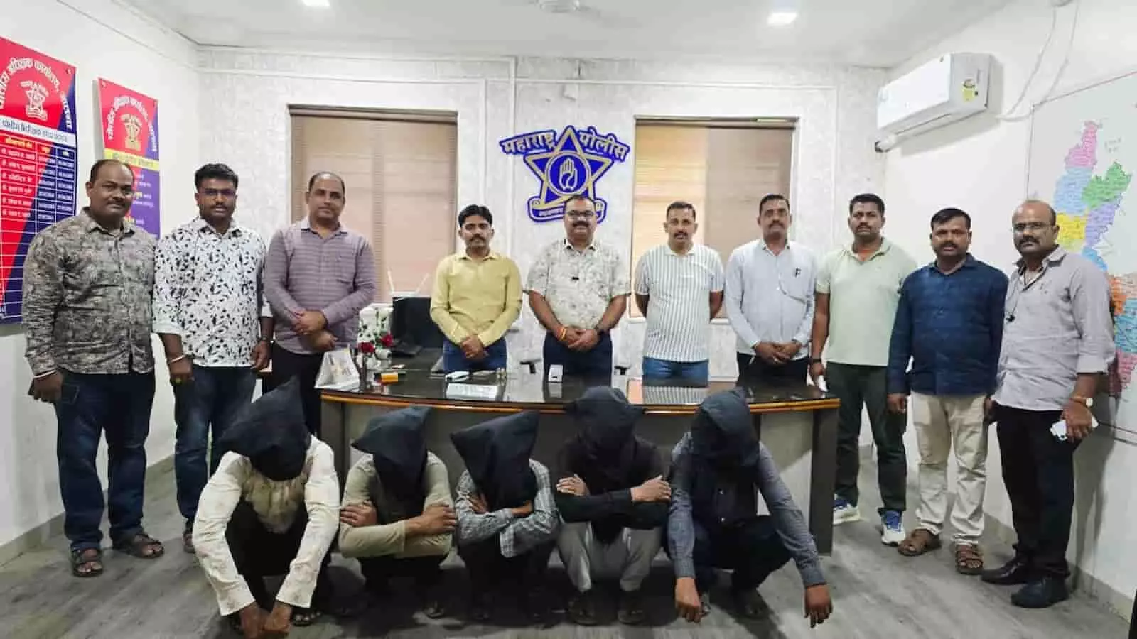 पुलिस कार्यालय में पुलिस अधिकारियों के साथ हिरासत में बैठे पांच आरोपी दिख रहे हैं।