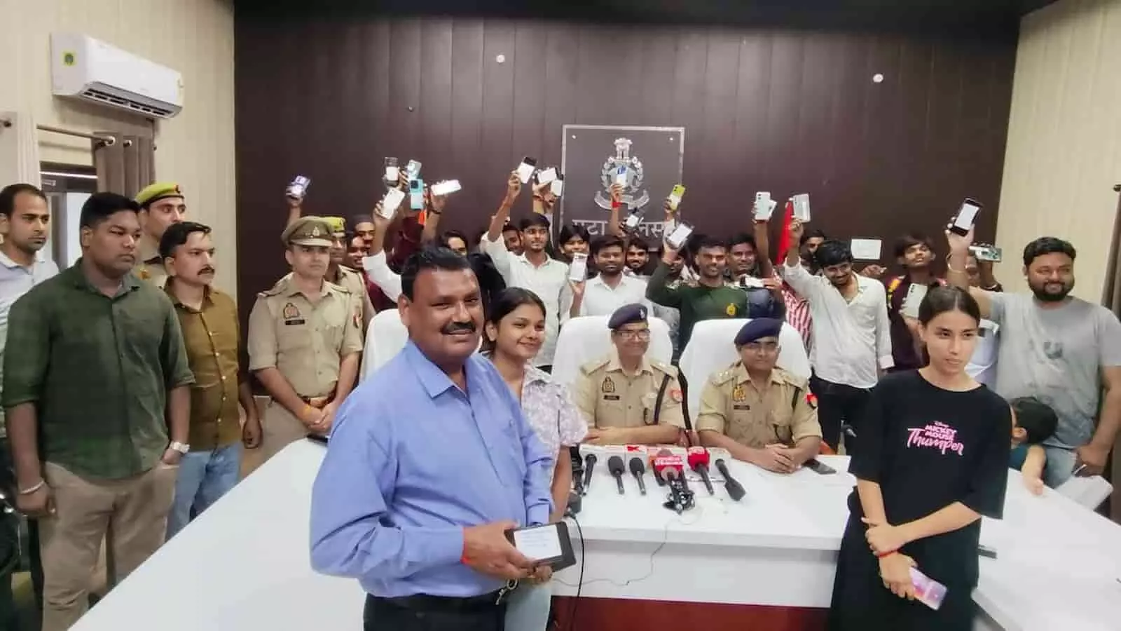 एटा पुलिस के अधिकारी बरामद किए गए मोबाइल फोन धारकों को सौंप रहे हैं।