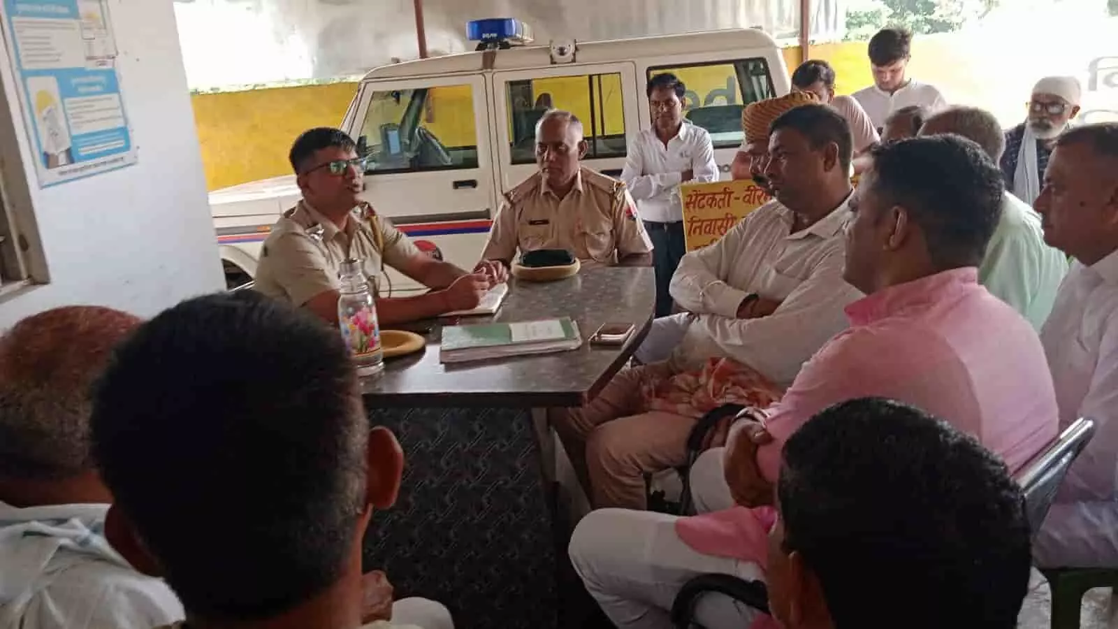 खेड़ली मोड थाना परिसर में मेज पर बैठकर बैठक लेते पुलिस अधिकारी और सामने बैठे नागरिक। खेड़ली मोड थाना परिसर में मेज पर बैठकर बैठक लेते पुलिस अधिकारी और सामने बैठे नागरिक।