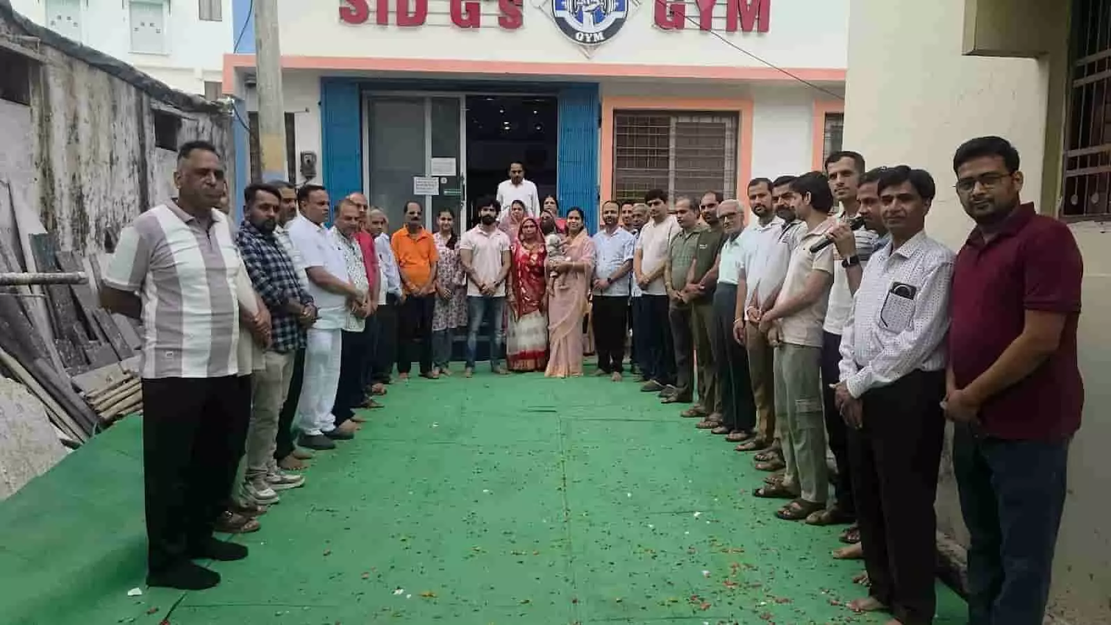 तस्वीर में रामधुन कार्यक्रम के दौरान एक इमारत के बाहर हरे कालीन पर कतार में खड़े श्रद्धालु दिख रहे हैं। तस्वीर में रामधुन कार्यक्रम के दौरान एक इमारत के बाहर हरे कालीन पर कतार में खड़े श्रद्धालु दिख रहे हैं।