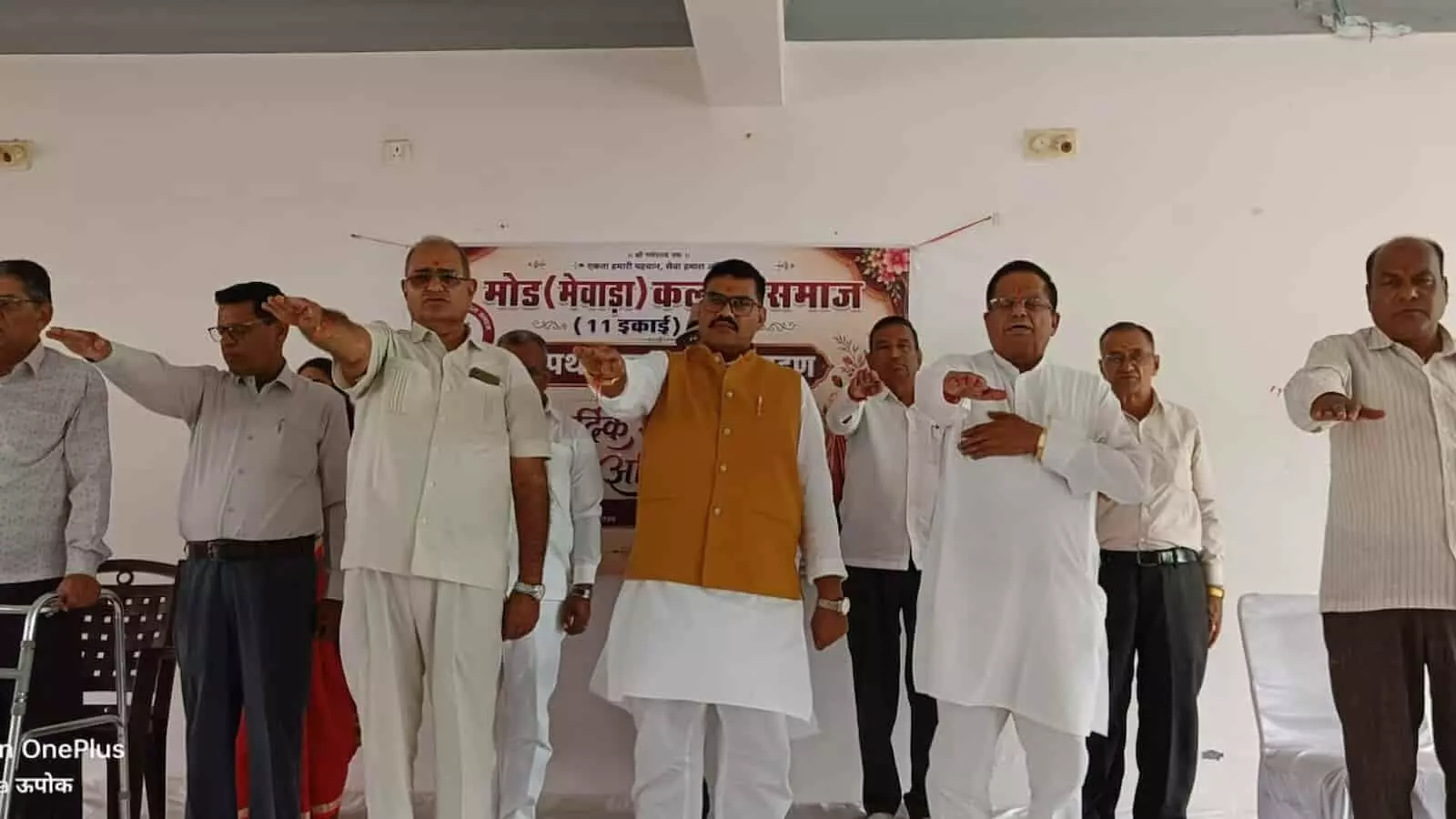 तस्वीर में समाज भवन के मंच पर खड़े पुरुष आगे हाथ बढ़ाकर सामूहिक रूप से शपथ ले रहे हैं। तस्वीर में समाज भवन के मंच पर खड़े पुरुष आगे हाथ बढ़ाकर सामूहिक रूप से शपथ ले रहे हैं।