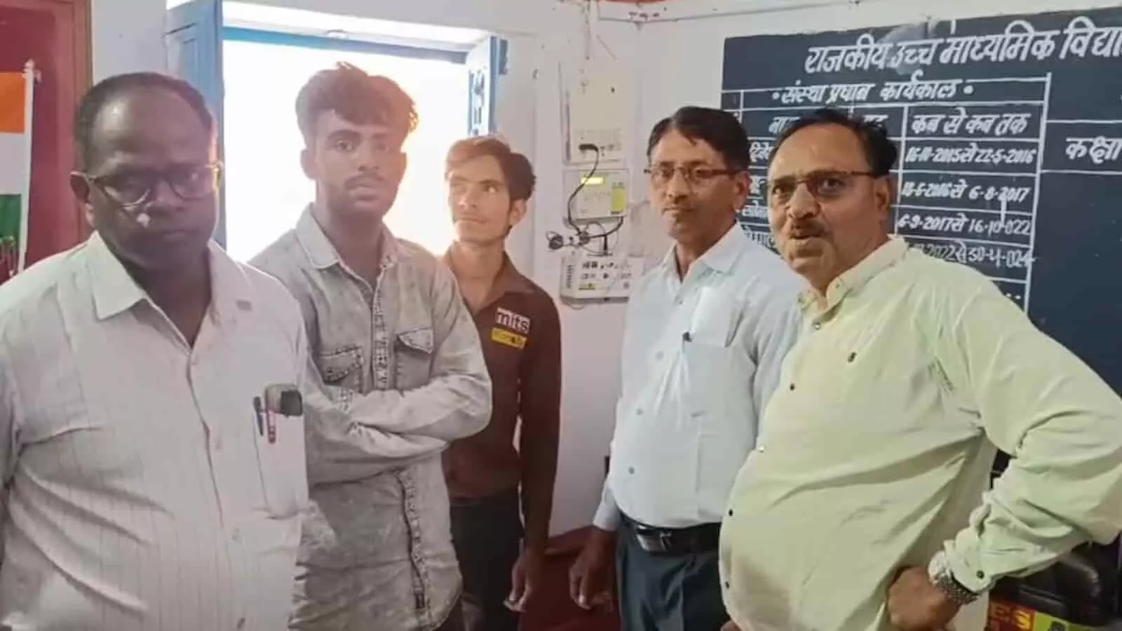 विद्यालय के कक्ष में मन्नूलाल खराड़ी और अन्य लोग घंटी भेंट कार्यक्रम में खड़े हैं। विद्यालय के कक्ष में मन्नूलाल खराड़ी और अन्य लोग घंटी भेंट कार्यक्रम में खड़े हैं।