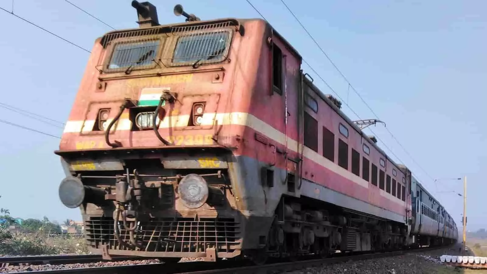 पटरी पर चल रहा भारतीय रेल का लाल रंग का इलेक्ट्रिक इंजन दिख रहा है। पटरी पर चल रहा भारतीय रेल का लाल रंग का इलेक्ट्रिक इंजन दिख रहा है।