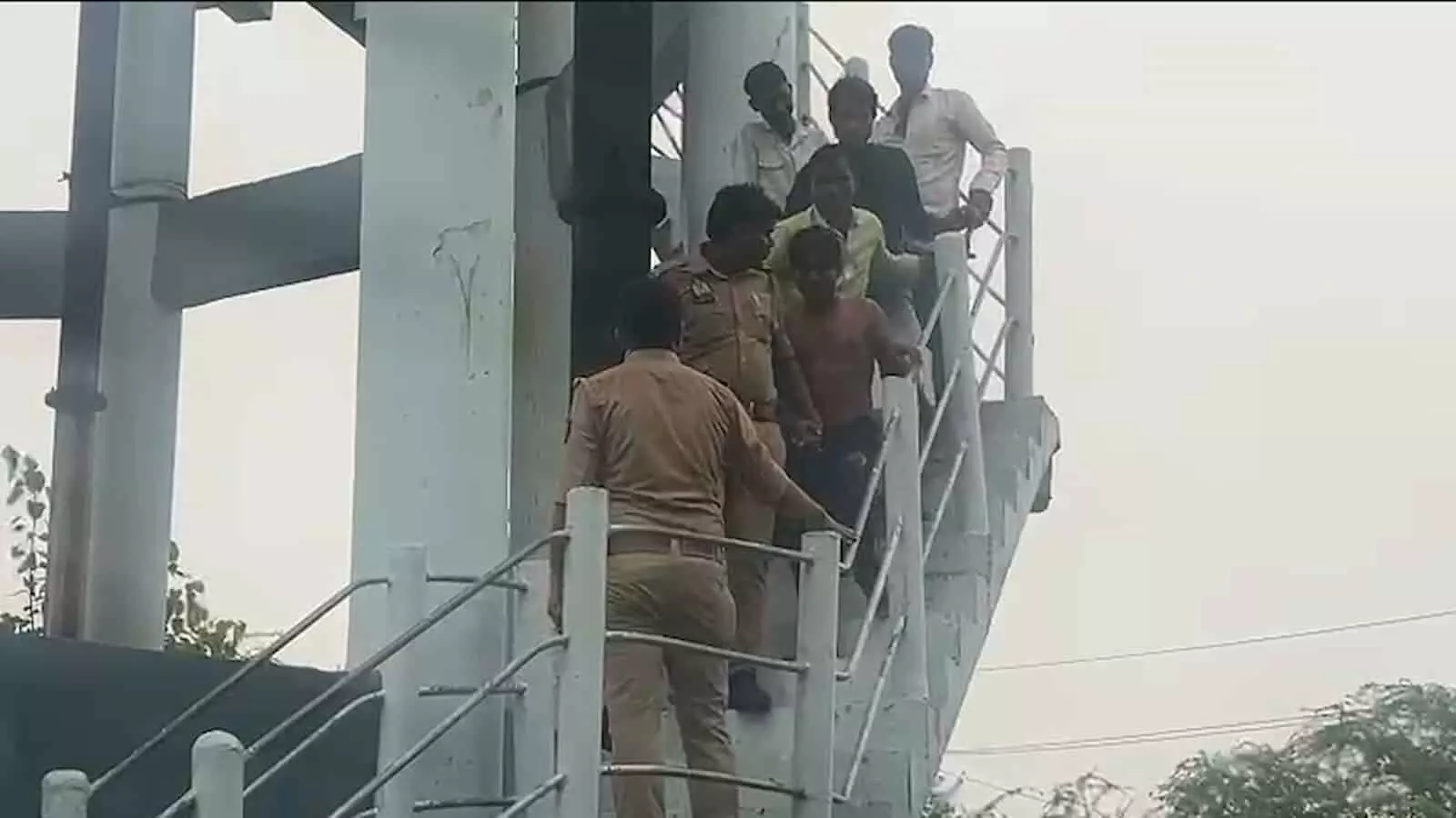 पुलिसकर्मी पानी की टंकी से एक युवक को नीचे उतार रहे हैं। पुलिसकर्मी पानी की टंकी से एक युवक को नीचे उतार रहे हैं।