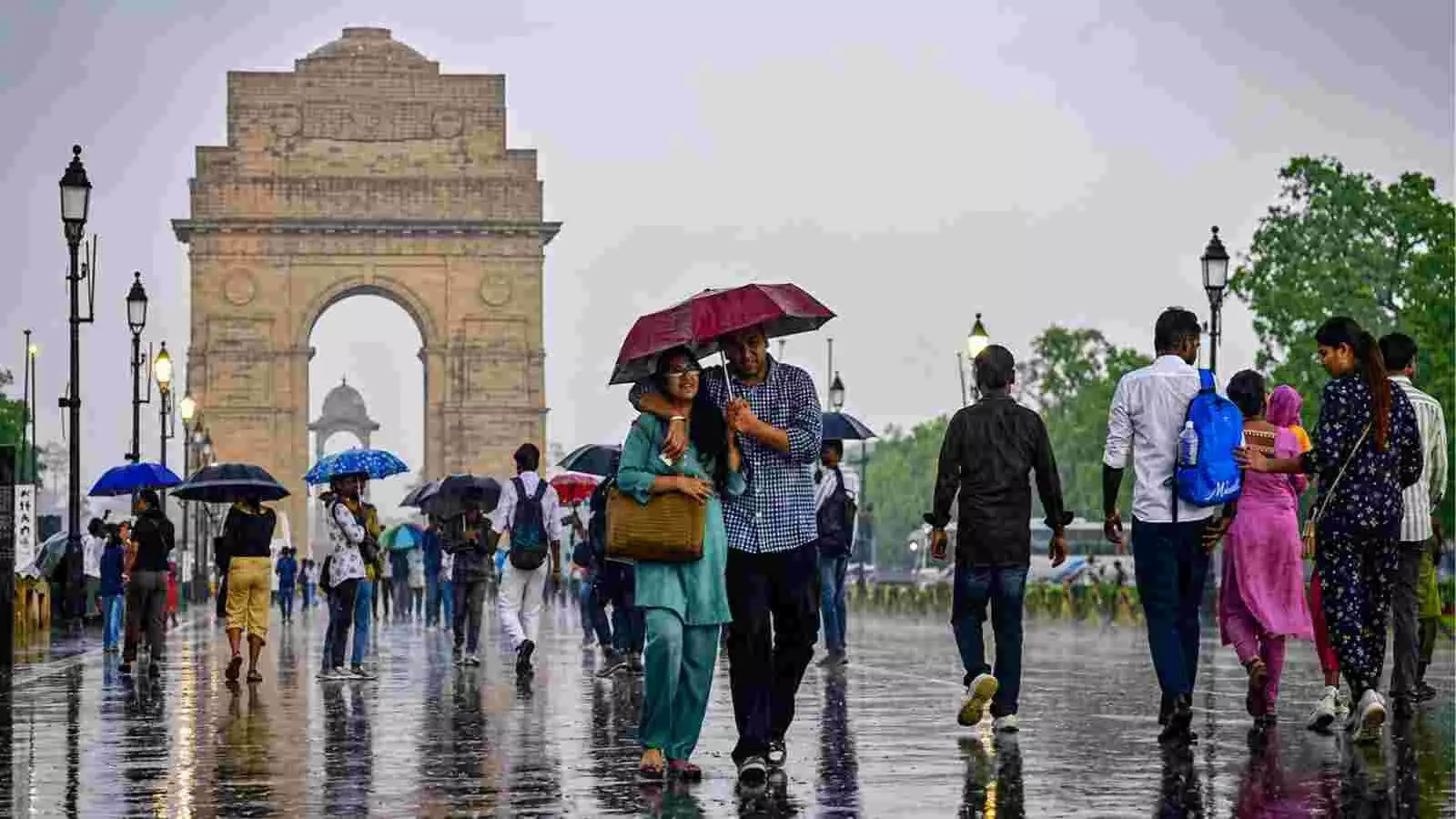 बारिश में छाता लेकर चलते लोग दिल्ली में इंडिया गेट के पास ।