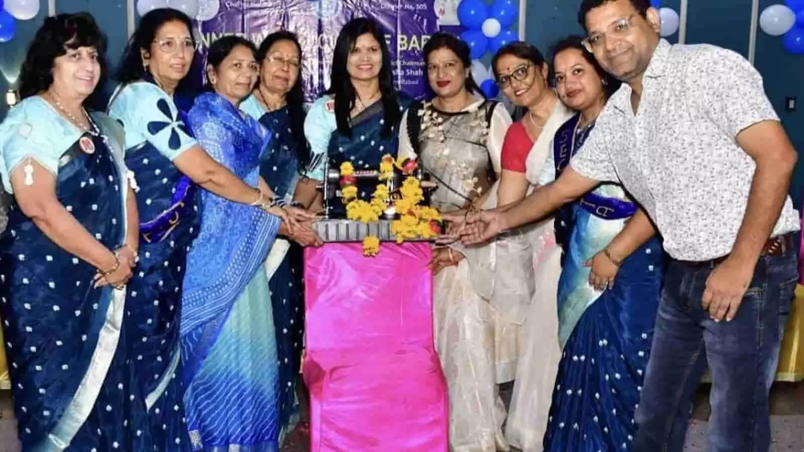 तस्वीर में इनरव्हील क्लब बारां के सदस्य एक सिलाई मशीन के पास खड़े हैं।