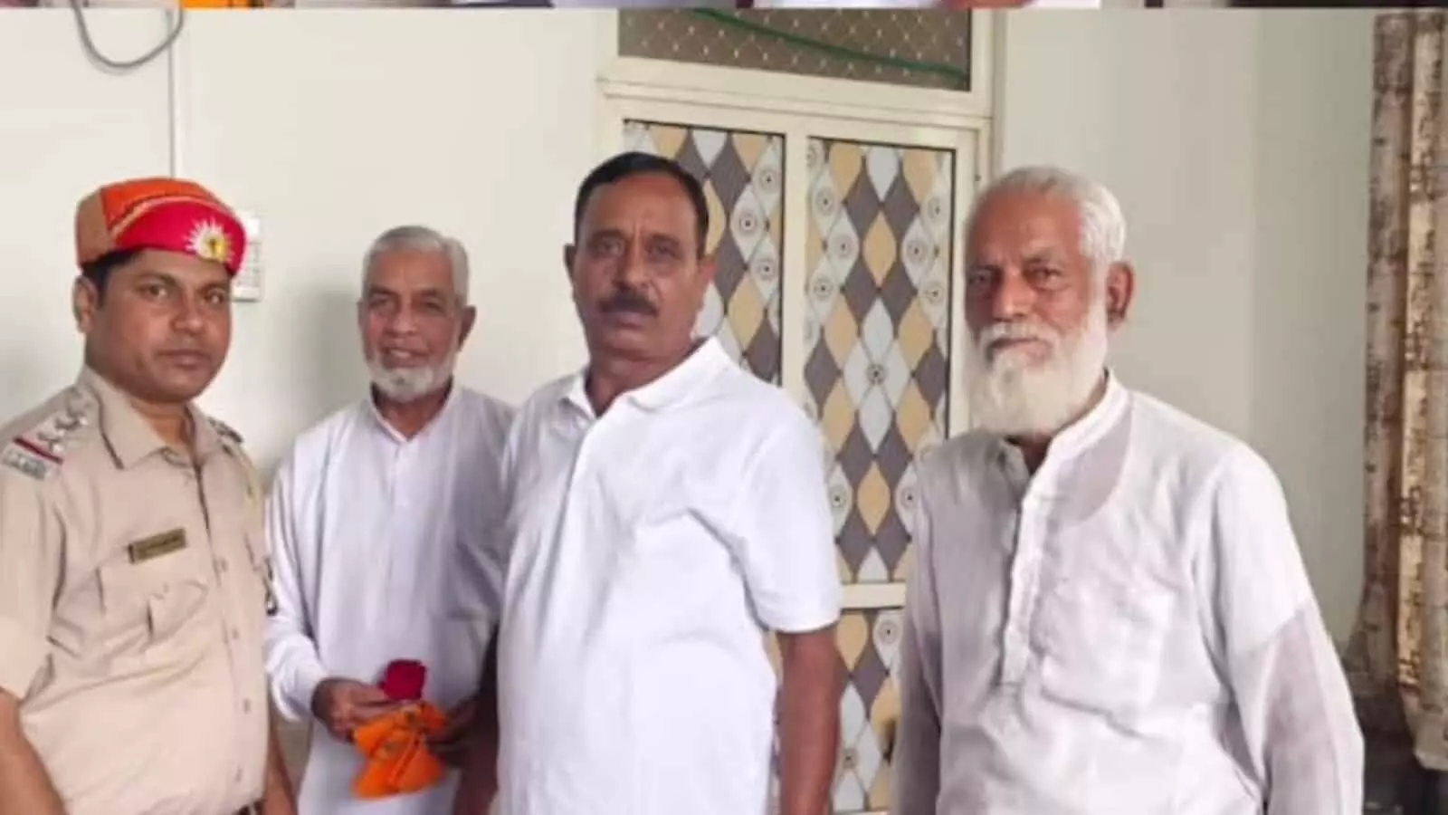 तस्वीर में पुलिस अधिकारी राजेश मीणा और समाज के प्रतिनिधि एक कमरे में खड़े हैं। तस्वीर में पुलिस अधिकारी राजेश मीणा और समाज के प्रतिनिधि एक कमरे में खड़े हैं।