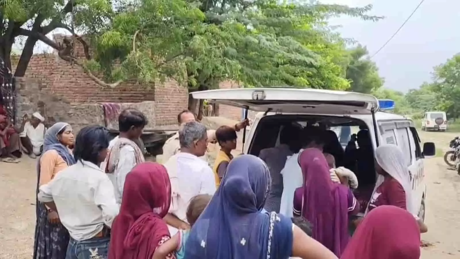 तस्वीर में गांव के रास्ते पर पुलिस वैन के पास खड़े ग्रामीण और पुलिसकर्मी दिख रहे हैं। तस्वीर में गांव के रास्ते पर पुलिस वैन के पास खड़े ग्रामीण और पुलिसकर्मी दिख रहे हैं।