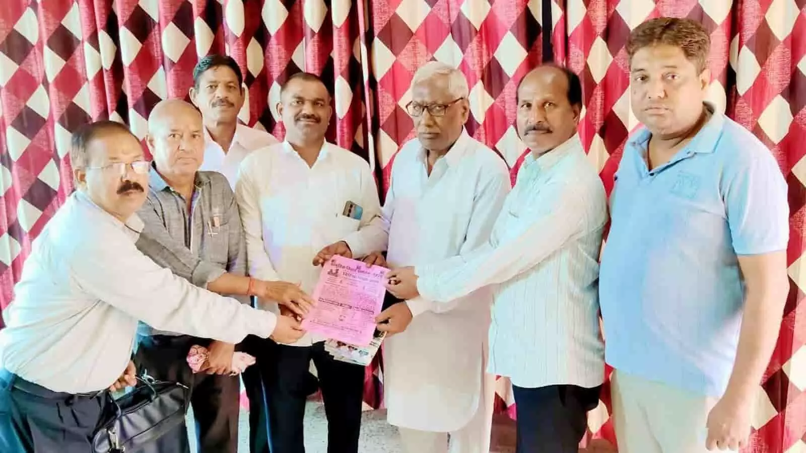 तस्वीर में समाज के लोग दूनी में सामूहिक विवाह सम्मेलन की निमंत्रण पत्रिका दिखाते हुए।
